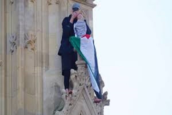 A barefoot man holds the Palestinian flag climbing Burj Ben